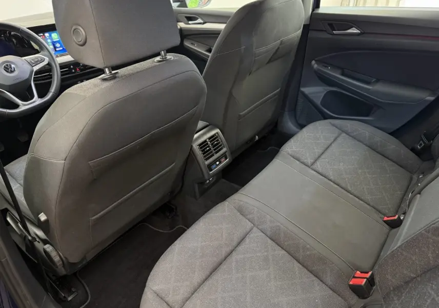 Vue intérieure arrière côté droit de la Volkswagen Golf bleu 2021, montrant les sièges et la console centrale avec aérateurs.