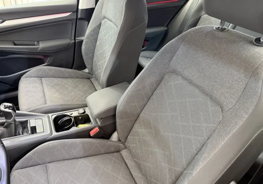 Vue intérieure rapprochée des sièges avant gris et de la console centrale avec levier de vitesse manuelle d’une Volkswagen Golf 2021.