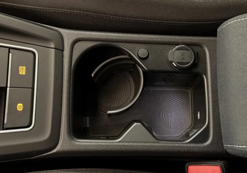 Vue rapprochée de la console centrale noire d’une Volkswagen Golf 2.0 TDI 2021 avec prise 12V et zone de recharge sans fil.