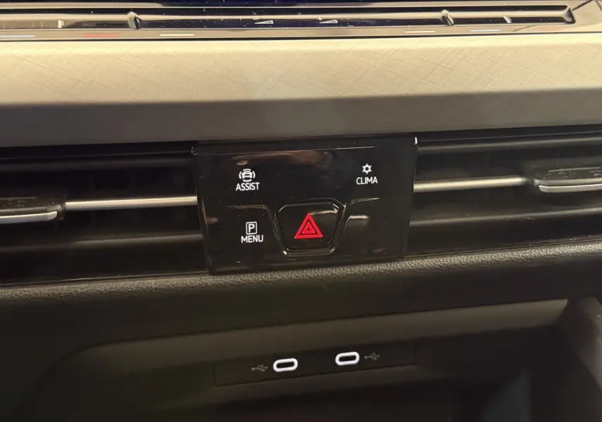 Gros plan sur la console centrale noire de la Volkswagen Golf bleu 2021, avec boutons d'alerte et climatisation.