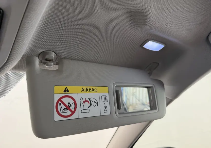Détail du pare-soleil côté conducteur avec miroir intégré et avertissement airbag dans un Volkswagen Golf bleu 2021.