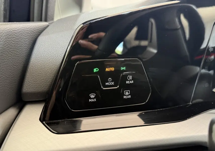 Gros plan sur le panneau de commande d’éclairage noir brillant du tableau de bord intérieur d’une Volkswagen Golf bleue.