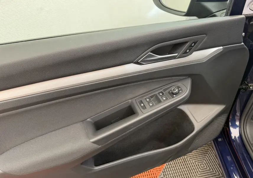 Vue rapprochée de la porte avant gauche bleu foncé de la Volkswagen Golf 2.0 TDI avec commandes électriques et poignée argentée.