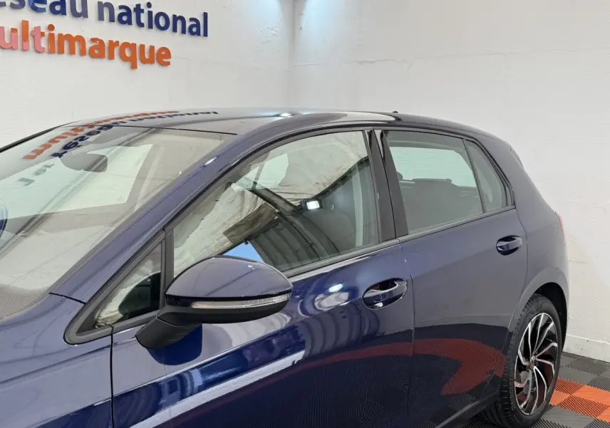 Vue côté gauche d'une Volkswagen Golf bleu métallisé 5 portes avec rétroviseur noir et jantes alliage distinctives.