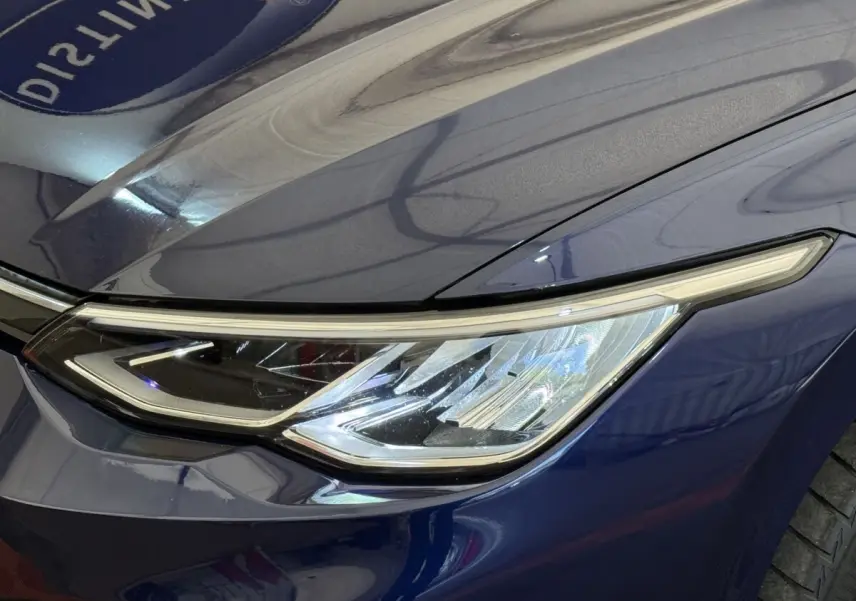 Gros plan sur le phare avant droit bleu métallisé d'une Volkswagen Golf 2.0 TDI 2021 avec ligne LED distinctive.