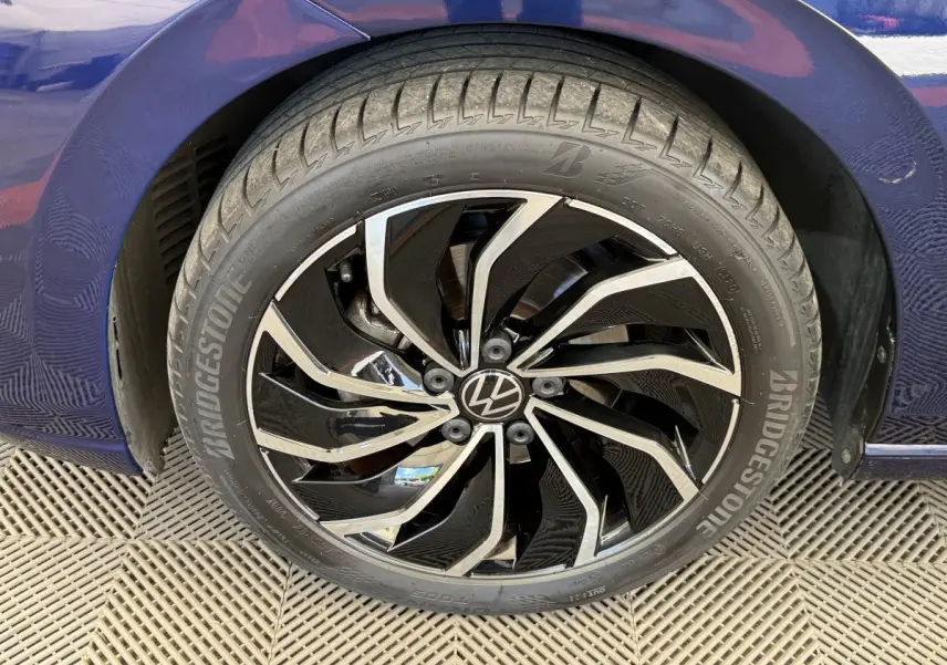 Gros plan sur la roue avant droite d’une Volkswagen Golf bleu 2021 avec jante noire et argentée au design moderne.