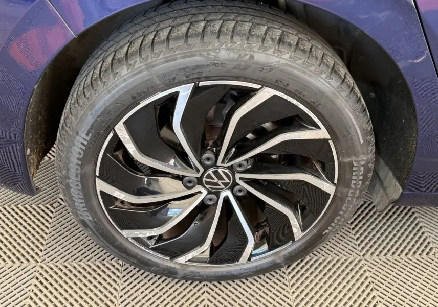 Gros plan sur la roue avant droite d’une Volkswagen Golf bleu 2021 avec jante noire et argentée au design dynamique.