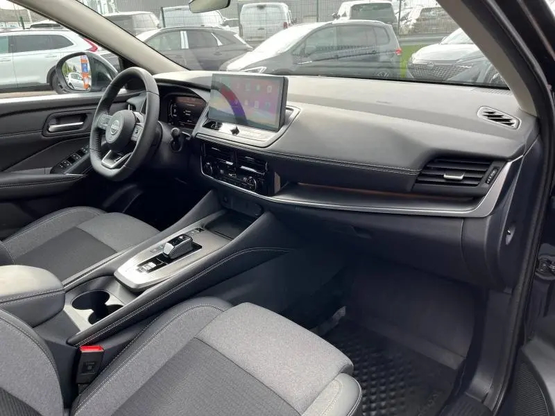 Intérieur avant droit du Nissan Qashqai e-POWER 2024, tableau de bord noir avec écran tactile et sièges tissu noir.
