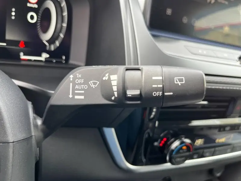 Gros plan sur la commande d'essuie-glace du Nissan Qashqai e-POWER 2024, intérieur noir avec tableau de bord digital.