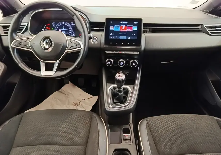 Vue intérieure avant de la Renault Clio Intens TCe 100 2020, tableau de bord noir avec écran tactile et levier de vitesse manuel.