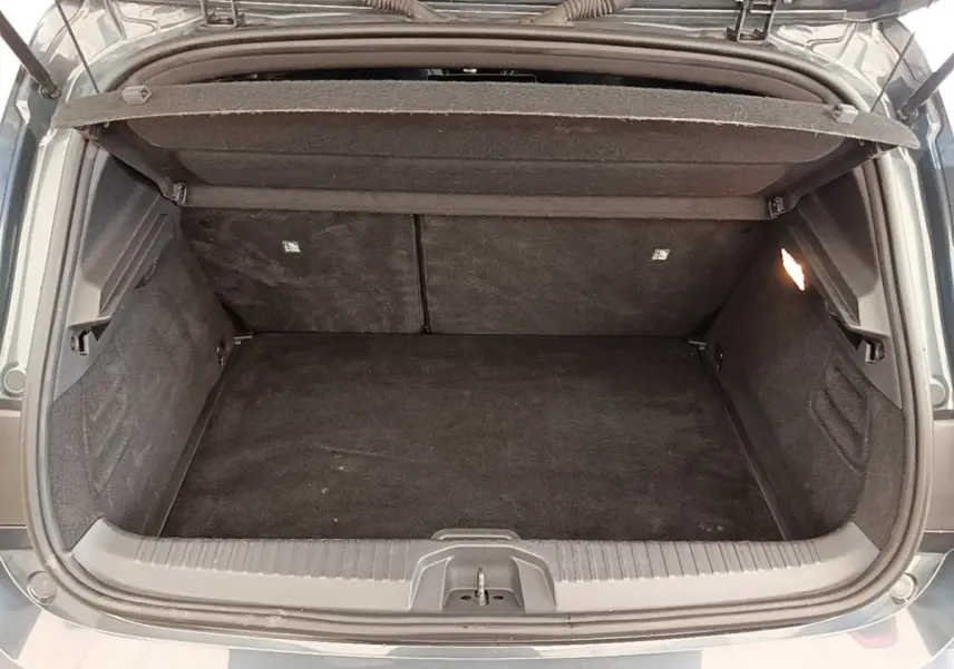 Coffre ouvert vu de l'arrière d'une Renault Clio Intens TCe 100 gris foncé, montrant l'espace de chargement vide.
