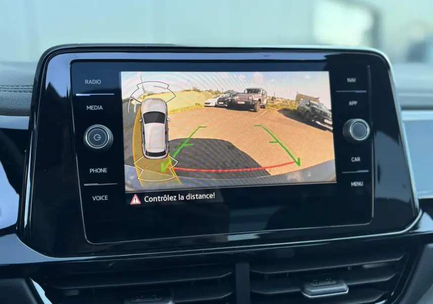Écran tactile intérieur du Volkswagen T-Roc affichant la caméra de recul avec alertes de distance active.
