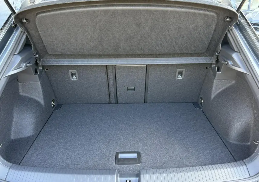 Coffre ouvert du Volkswagen T-Roc gris Indium, montrant l'espace de chargement et la garniture intérieure grise.