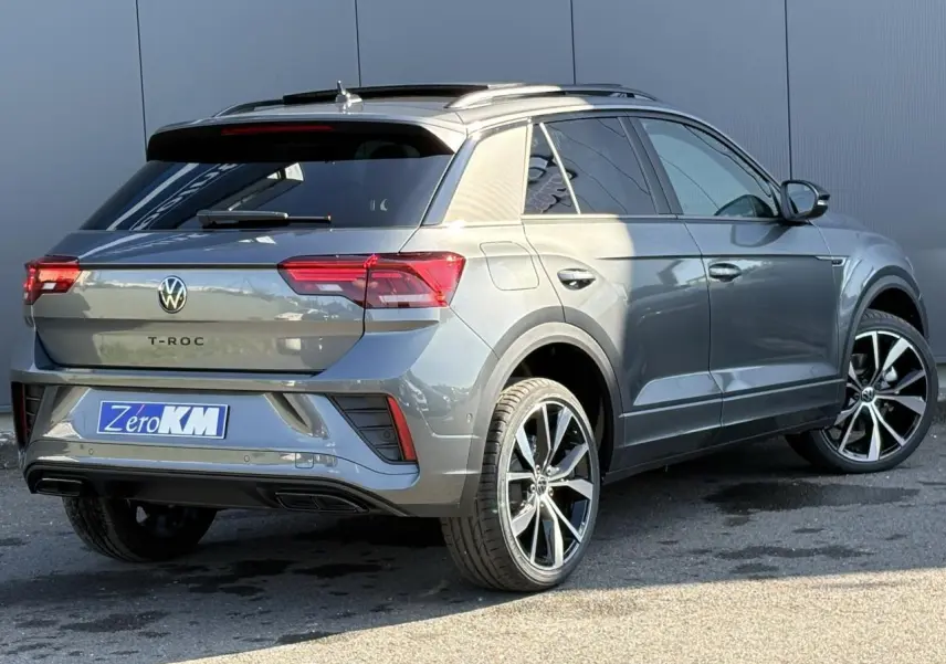 Volkswagen T-Roc gris Indium en 3/4 arrière droit avec jantes alliage 19 pouces et toit ouvrant visible.