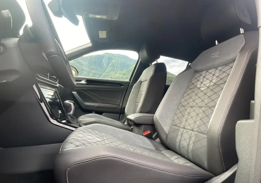 Vue intérieure côté conducteur du Volkswagen T-Roc 2025 R-Line Black avec sièges en cuir et alcantara gris à motifs.
