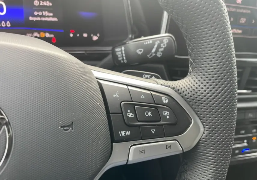 Gros plan sur le volant perforé du Volkswagen T-Roc 2025 R-Line Black avec commandes multifonctions visibles.