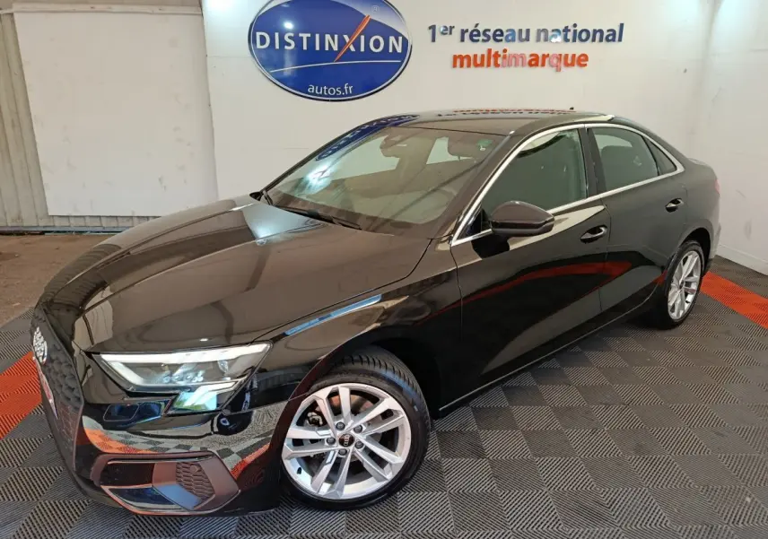 Audi A3 30 TFSI MHEV Business Line noire vue en 3/4 avant droit dans un showroom avec logo Distinxion en arrière-plan
