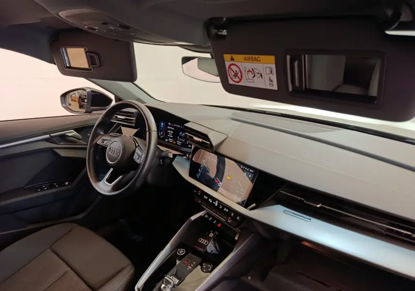 Vue intérieure côté conducteur de l'Audi A3 30 TFSI MHEV 2022, tableau de bord moderne avec écran tactile et volant cuir.