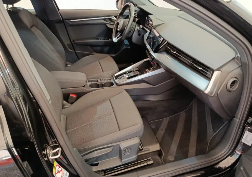 Intérieur avant droit d'une Audi A3 noire 2022, sièges tissu gris, tableau de bord moderne avec écran tactile.