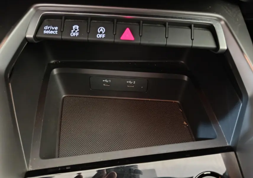 Vue rapprochée de la console centrale noire de l'Audi A3 30 TFSI MHEV avec boutons de contrôle et ports USB visibles.