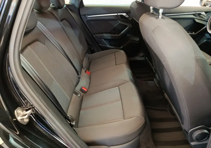 Vue intérieure côté gauche sur la banquette arrière grise de l'Audi A3 30 TFSI MHEV Business Line 2022 noire.