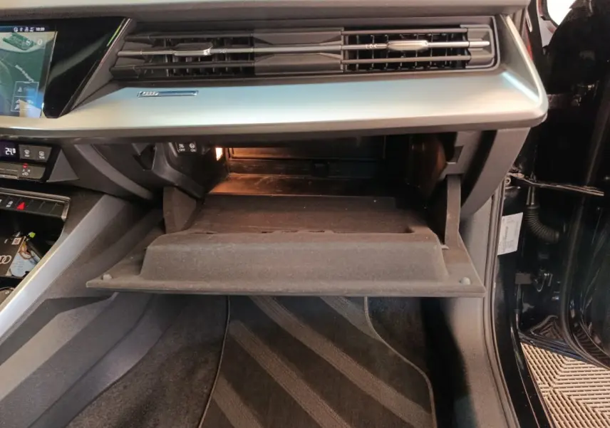 Intérieur de l'Audi A3 2022 noir, vue sur la boîte à gants ouverte côté passager avec tableau de bord gris.