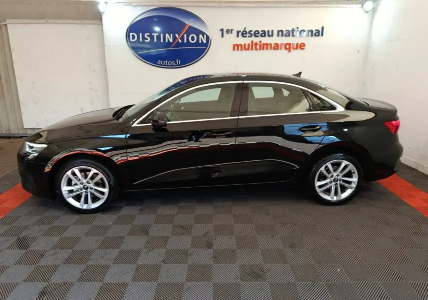 Audi A3 30 TFSI MHEV noir vue de profil côté gauche dans un showroom avec sol à damier noir et rouge.