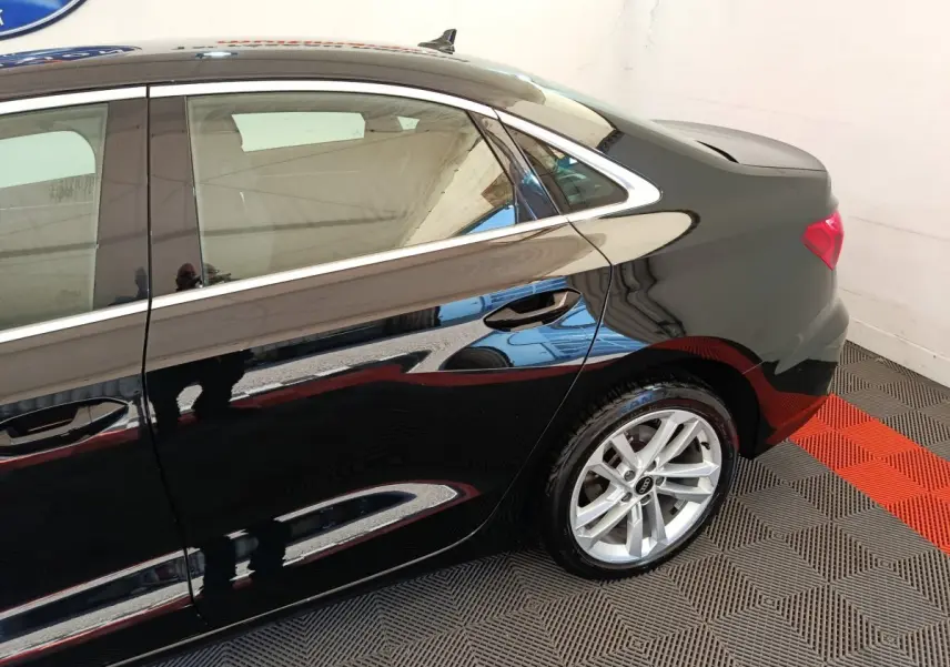 Profil arrière droit d'une Audi A3 noire brillante, mettant en valeur la jante alliage et la ligne de toit élégante.