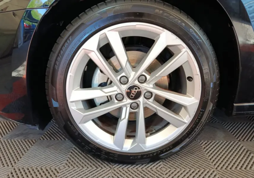 Gros plan sur la jante argentée de l'Audi A3 noire, mettant en valeur le logo Audi au centre de la roue.