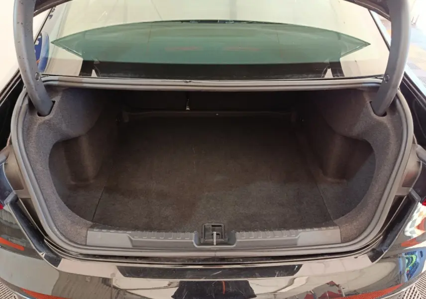 Coffre ouvert vu de l'arrière d'une Audi A3 noire 2022, espace de rangement vide et tapis gris foncé.