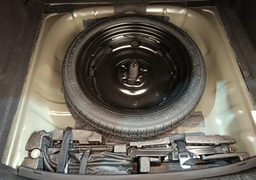 Vue plongeante sur la roue de secours noire et le coffre à outils dans le compartiment arrière d'une Audi A3 noire 2022.