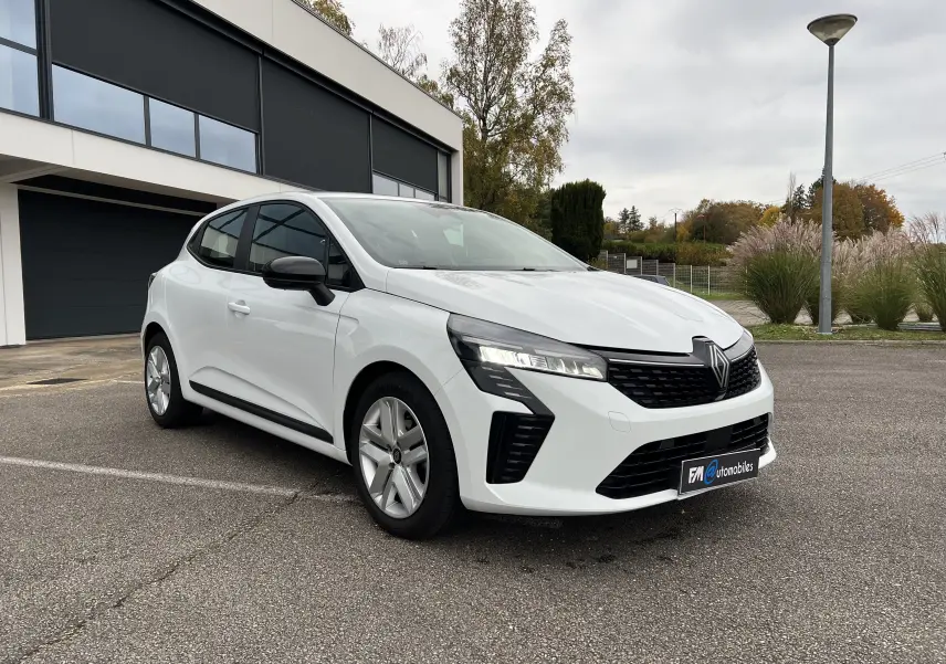 Renault Clio V blanche vue 3/4 avant droit, avec rétroviseurs noir perle et jantes 16 pouces en extérieur urbain.