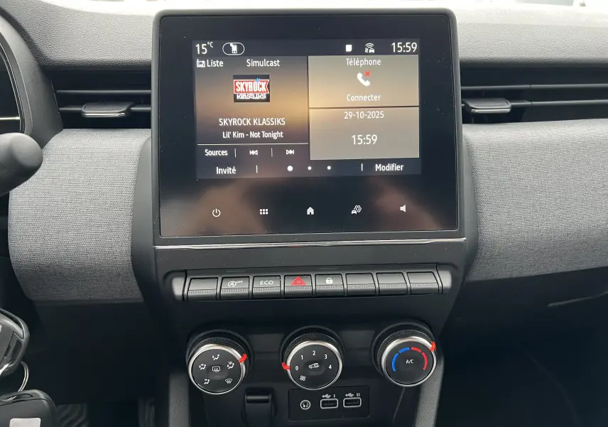 Tableau de bord de Renault Clio V blanc, vue frontale sur l'écran tactile multifonctions et commandes de climatisation.