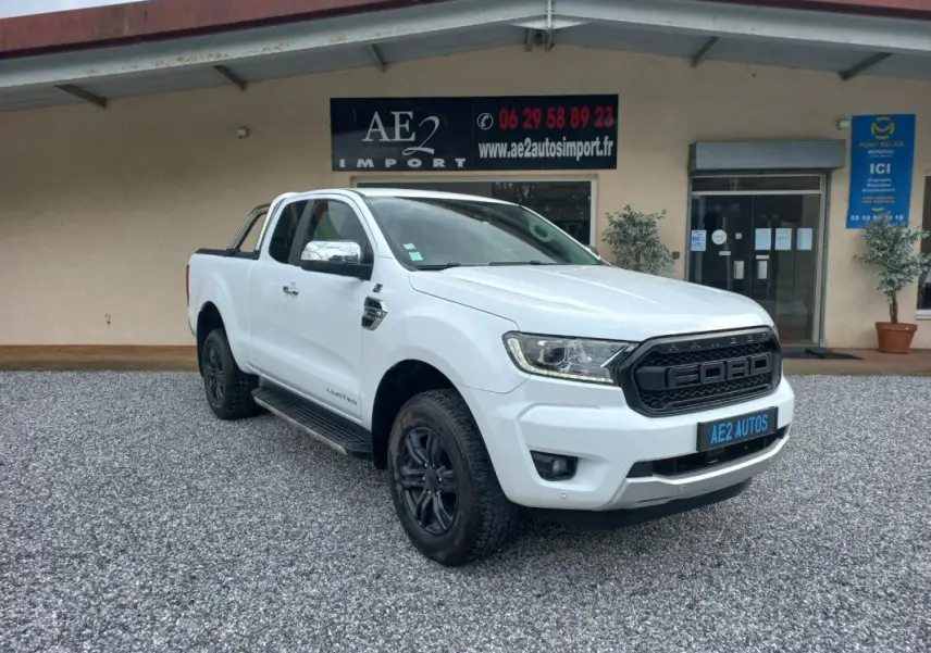 Ford Ranger Super Cabine Limited blanc vu en 3/4 avant droit avec calandre noire et jantes noires sur gravier.