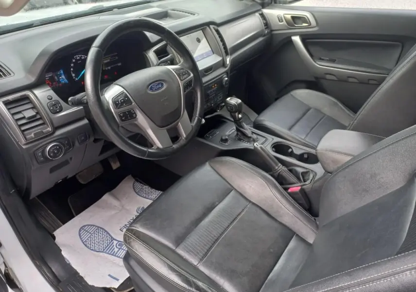 Vue intérieure côté conducteur du Ford Ranger 2022, montrant le volant, tableau de bord et sièges en cuir noir.