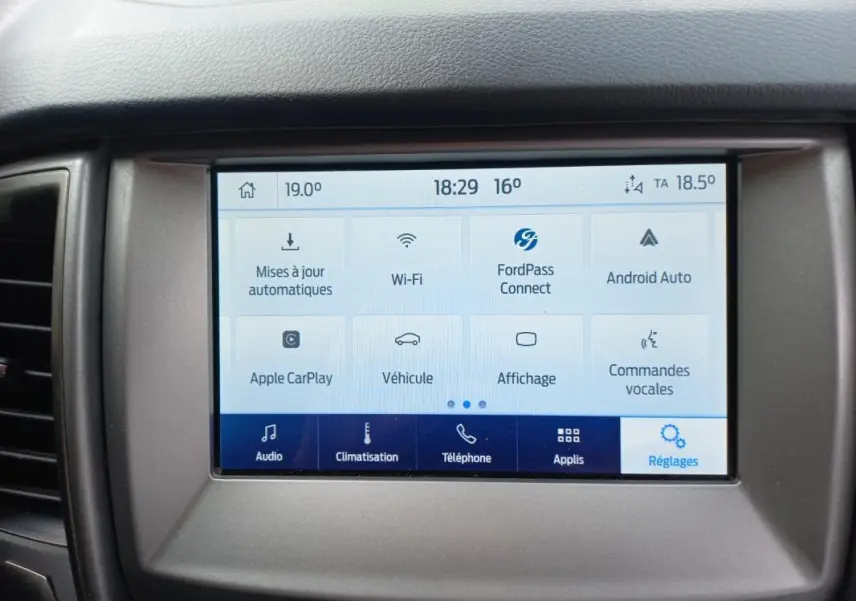 Tablette tactile centrale du Ford Ranger blanc 2022, affichant le menu des réglages avec options connectivité et climatisation.