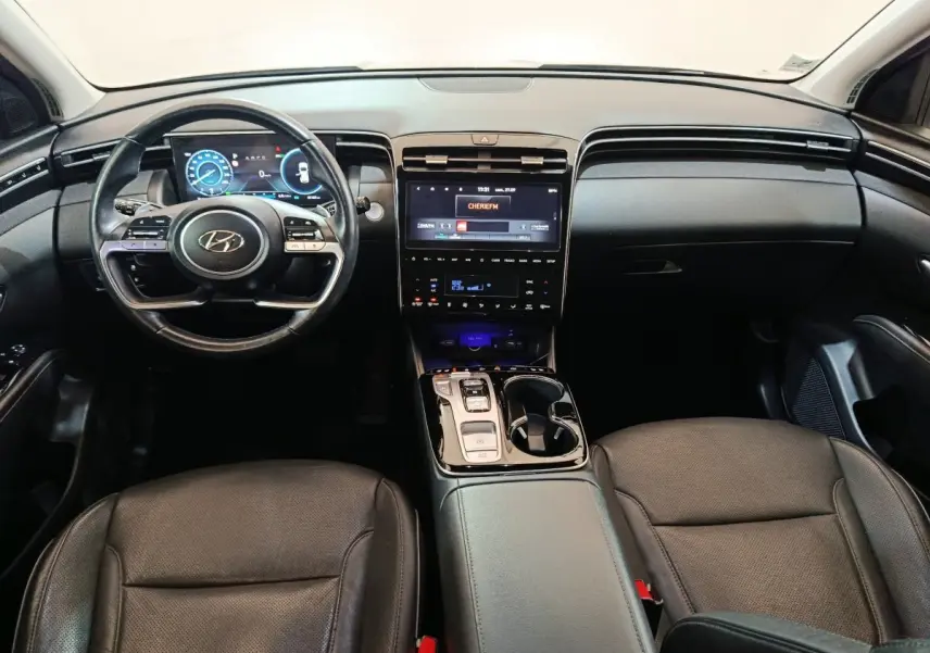 Intérieur noir du Hyundai Tucson 2022, vue frontale du tableau de bord avec écran tactile et volant multifonction.