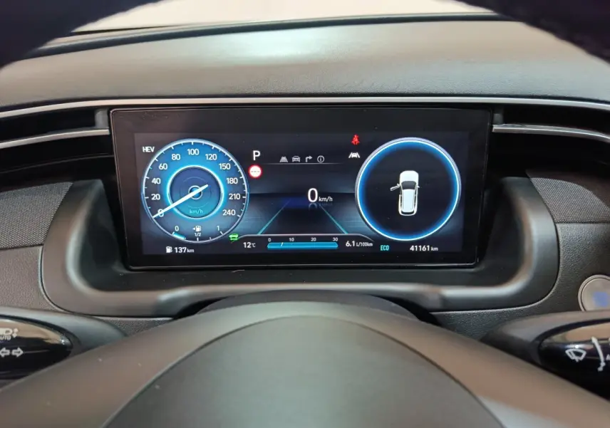 Tableau de bord numérique du Hyundai Tucson 2022 montrant vitesse et alertes, vue depuis le volant.