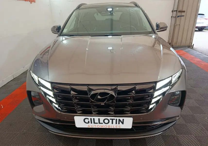 Vue avant d'un Hyundai Tucson marron 2022 avec calandre noire brillante et phares LED allumés.