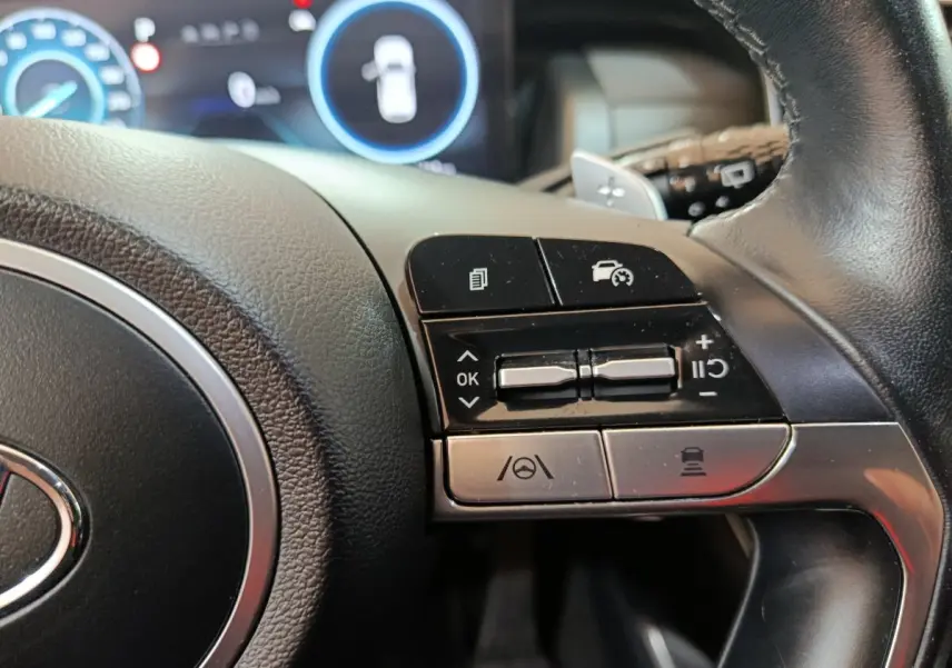 Gros plan sur les commandes du volant côté droit du Hyundai Tucson marron hybride rechargeable 2022 avec affichage digital.