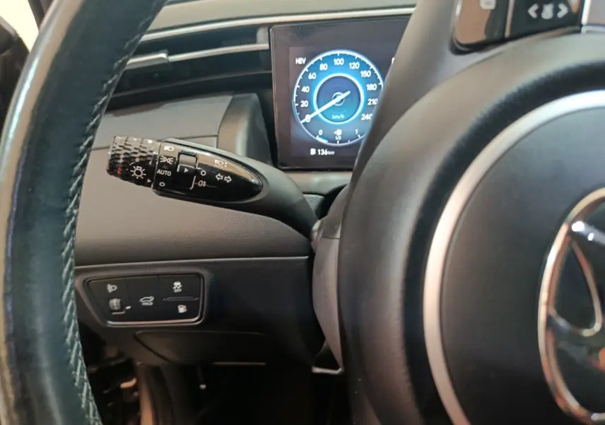 Gros plan sur le volant et le commodo gauche du Hyundai Tucson marron 2022, avec tableau de bord numérique affichant la vitesse.