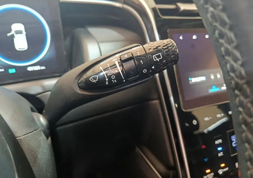 Gros plan sur la commande d'essuie-glace noire du Hyundai Tucson 2022, avec tableau de bord et écran tactile en arrière-plan.