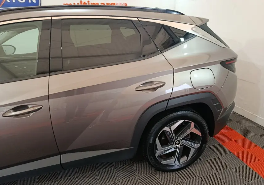 Vue latérale droite du Hyundai Tucson marron 2022, mettant en valeur la porte arrière et la roue arrière au design moderne.