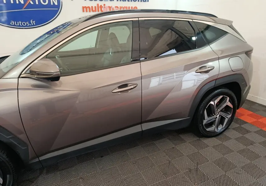 Vue latérale côté gauche du Hyundai Tucson marron 2022, soulignant ses lignes anguleuses et ses jantes modernes.