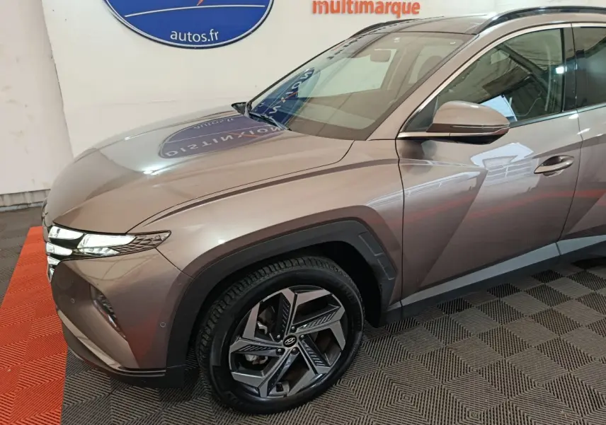 Vue 3/4 avant droit d'un Hyundai Tucson marron avec jantes alliage et phares LED distinctifs.