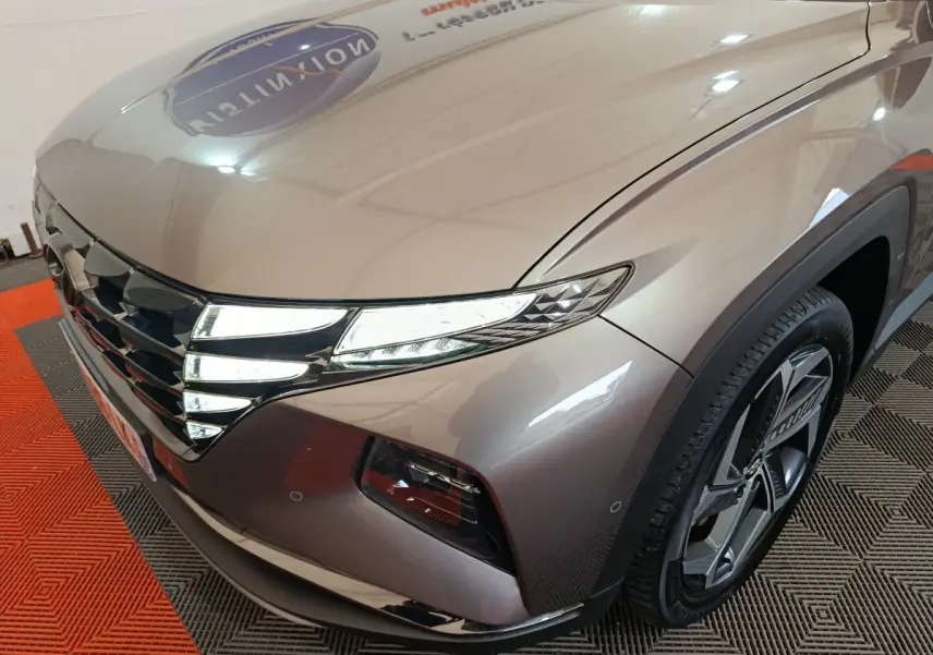 Vue 3/4 avant droit du Hyundai Tucson marron avec ses phares LED et jante alliage distinctifs.
