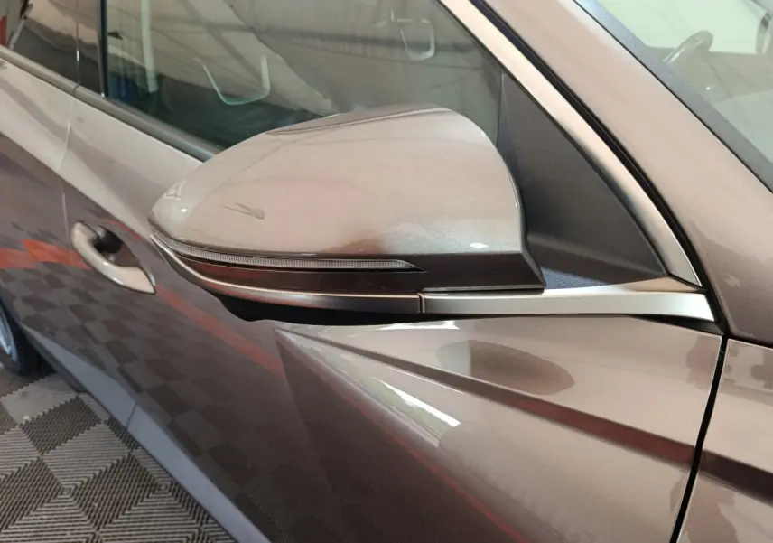Rétroviseur côté gauche marron du Hyundai Tucson 2022 avec clignotant intégré et poignée de porte visible.