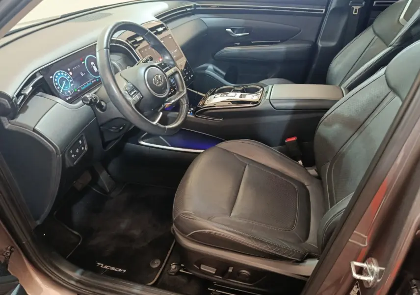 Intérieur côté conducteur du Hyundai Tucson marron 2022, mettant en valeur le volant cuir multifonctions et l'écran digital.