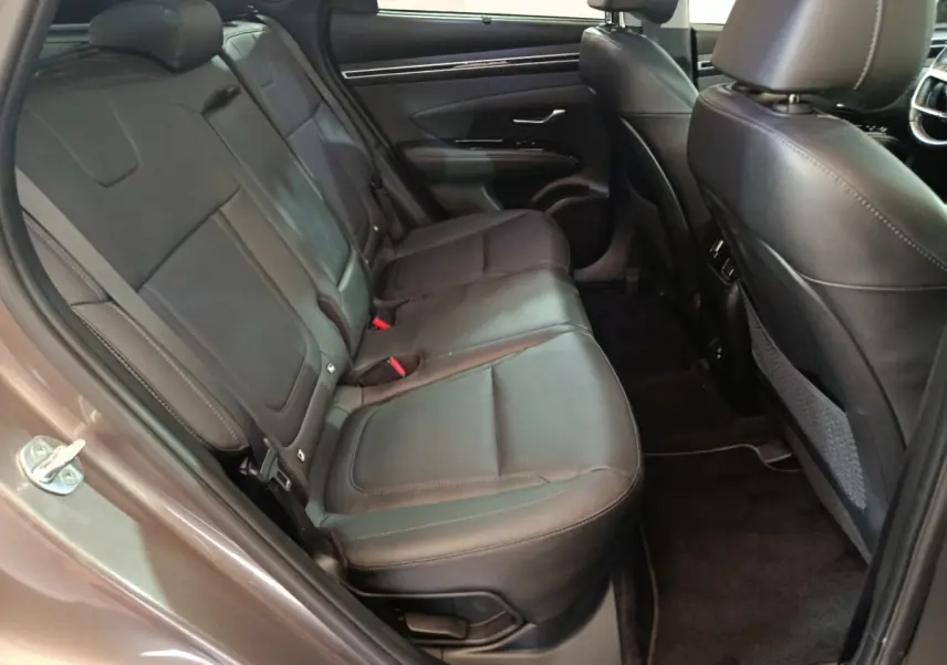 Vue intérieure côté gauche des sièges arrière en cuir noir du Hyundai Tucson marron 2022, avec porte ouverte.