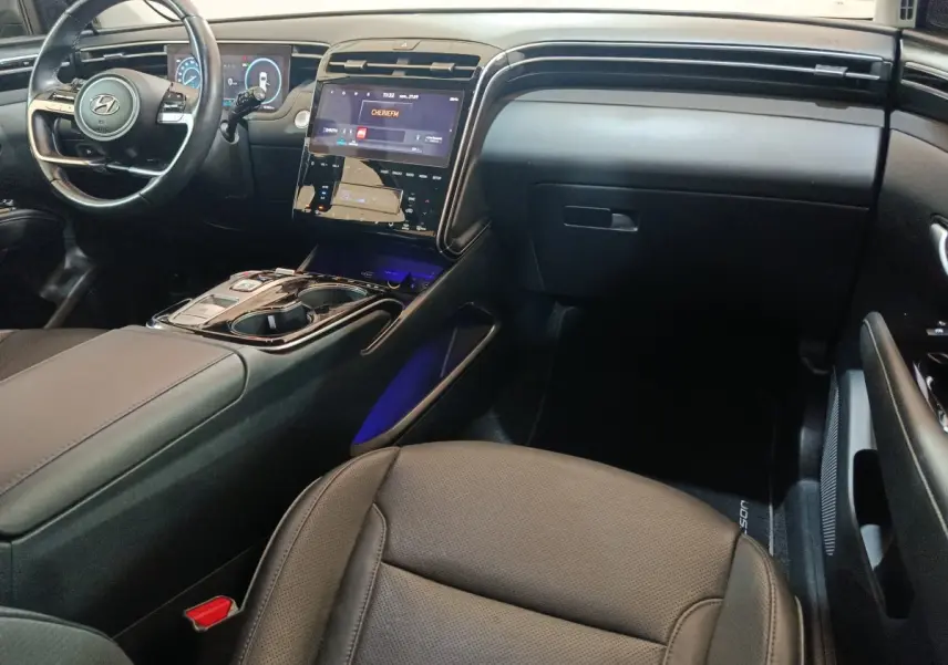 Intérieur noir du Hyundai Tucson 2022 vu côté passager, avec tableau de bord et écran tactile central lumineux.